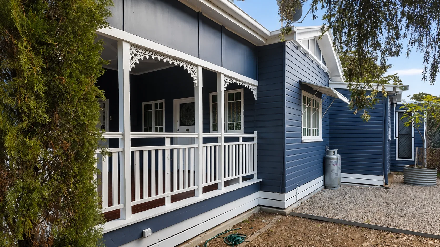 A Queenslander with a deep blue-grey exterior and white trims, painted by Paint Gods